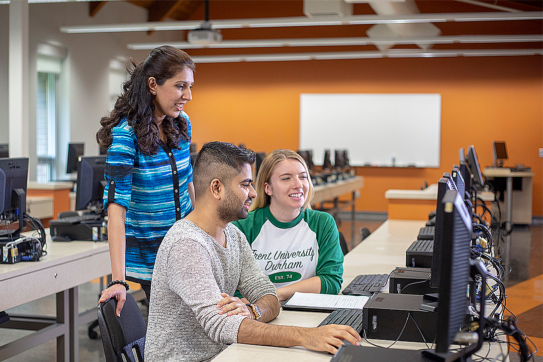 Faculty help two students at a computer