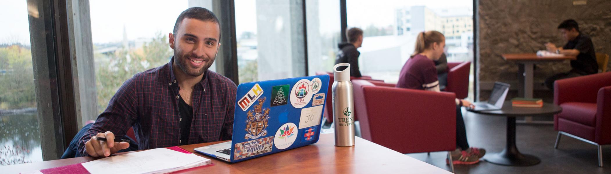 Trent University student sitting at a desk with a laptop in Bata library