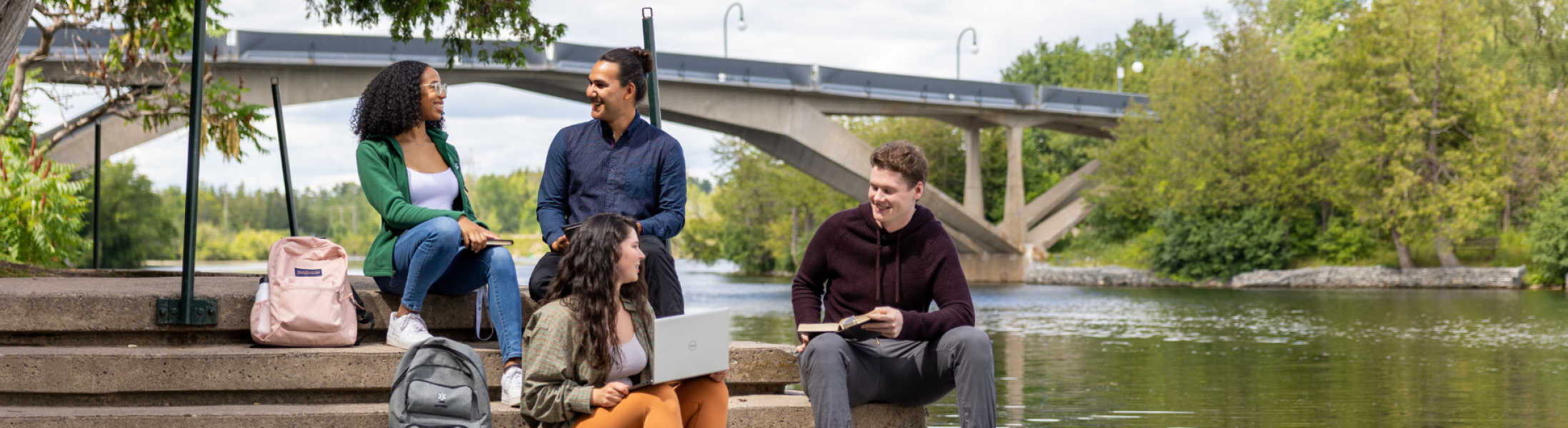 A group of Trent students sitting and talking by the Otonabee River