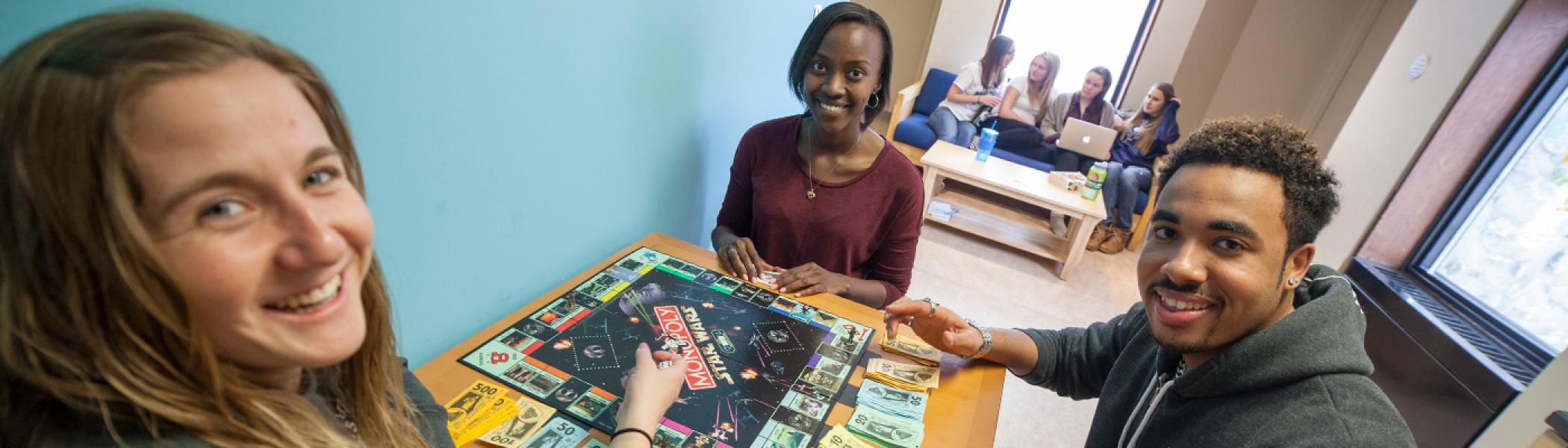 3 Students sitting at a lunch room table playing a board game in Otonabee college