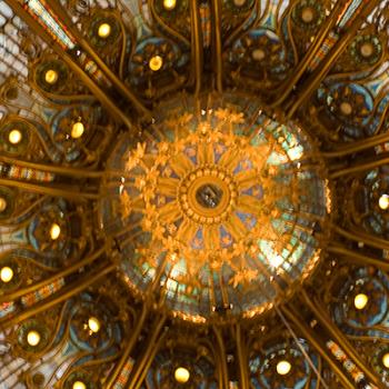 Looking up and intricate stained glass and gold ceiling with an ornate light in the centre. 