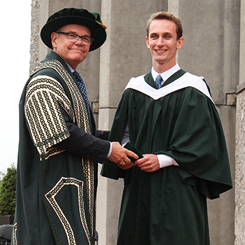 Student receiving an award at convocation on the podium outside of Bata Library in the early afternoon