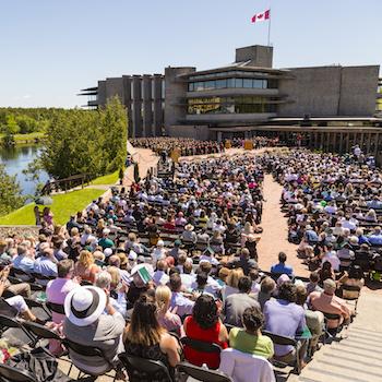 A crowd of people sitting in front of Bata Library during a convocation ceremony